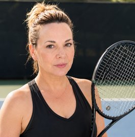 Liz at a tennis court holding a racket